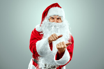 Portrait of Santa Claus in a red suit points his fingers, light background. Concept for christmas eve, vacation, holiday banner, new year.
