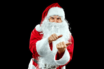 Portrait of Santa Claus in a red suit points his fingers, dark background isolate. Concept for christmas eve, vacation, holiday banner, new year.