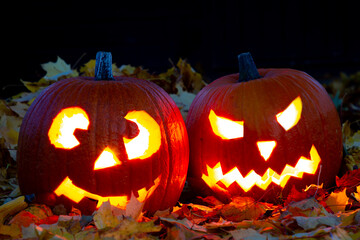 Obraz premium Couple of Halloween pumpkins lighting in the dark with funny and scary faces
