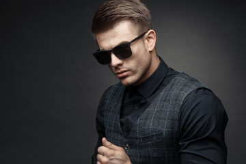 Portrait of beautyful guy on dark background. High fashion model posing in studio. Attractive man in classic suit.