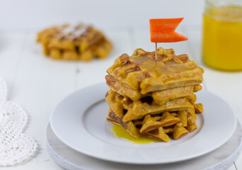 Carrot waffles with honey on white wooden background