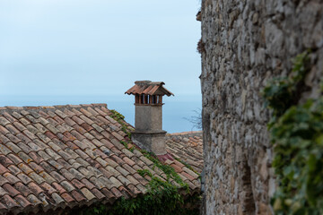 Old roof tiles and chimney. Wall covered with ivy. Eze Village, South of France. 