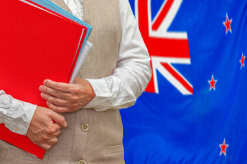 Woman holding red folder on New Zealand flag background. Education and jurisprudence concept in New Zealand