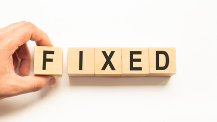 Word fixed. Wooden small cubes with letters isolated on white background with copy space available.Business and finance concept