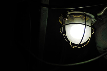 Industrial lantern on a wall in the dark, luminous round lamp. Mine, basement