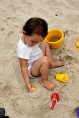 A baby playing on the beach with the sand and water.     