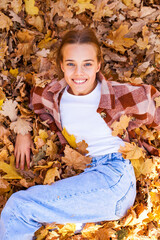 Portrait of a beautiful young woman on the background of autumn yellow leaves, outdoors