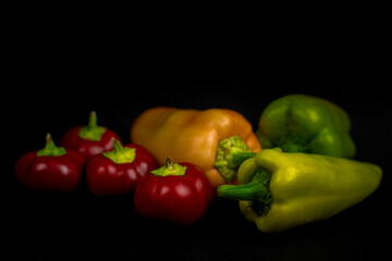 red, yellow and green peppers on black background