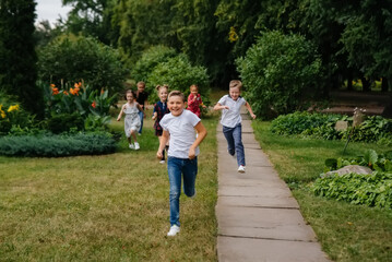 Obraz premium A group of school children runs in the Park in the summer. Happiness, lifestyle. Happy childhood