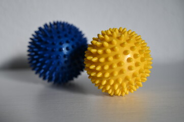 A yellow and a blue hand massage ball next to each other.