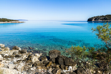 Beautiful idyllic turquoise waters coast with pebbles and rocks.