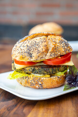 Eating of fresh and healthy vegetarian hamburgers with grilled spinach or pumpkin burgers, organic buns and vegetables