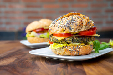 Eating of fresh and healthy vegetarian hamburgers with grilled spinach or pumpkin burgers, organic buns and vegetables
