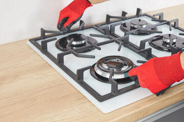 Male hand do installation grill on gas hob in kitchen. Repairs or fix of gas control panel.