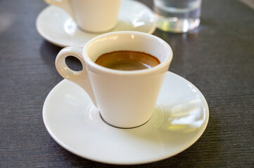 Drinking of strong black espresso coffee on outdoor terrace in cafe