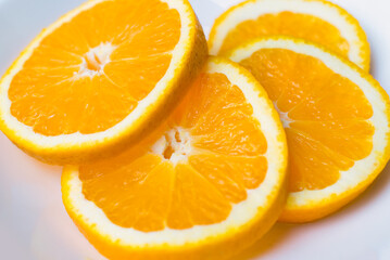 A few fresh slices of orange on a white plate. Top view, close up image