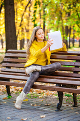 Young girl draws with a pencil in the sketchbook, autumn park outdoor