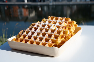 Sweet fresh baked Belgian waffles served outdoor with view on Maas river in Dinant, Wallonia, Belgium.