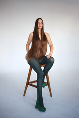 young beautiful woman with very long hair sits on a chair