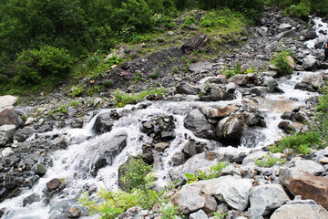 Midagrabindon  waterfalls in the gorge. Mountains in the North Caucasus in summer. Mountain tops in the clouds.