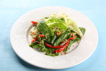 Healthy food. Fresh lettuce salad with quinoa and red pepper on a white plate on a blue background. Background image, copy space