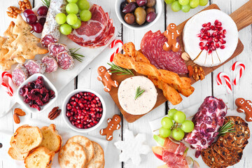 Christmas theme charcuterie table scene against a white wood background. Variety of cheese and meat...