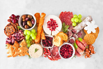 Christmas theme charcuterie board. Top view against a white marble background. Variety of cheese...