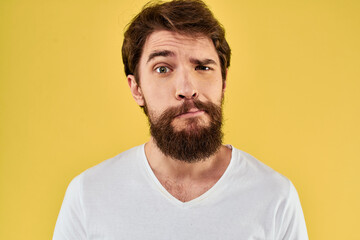 Obraz premium A man in a white t-shirt gestures with his hands lifestyle cropped view yellow background more fun