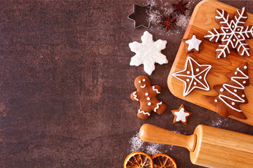 Christmas baking side border with gingerbread cookies. Overhead view over a dark stone background with copy space. Holiday baking concept.