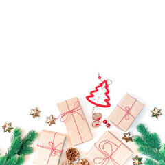Christmas composition. Gifts in craft paper are tied with striped twine. Fir branches and festive decorations are nearby. White background. Flat lay. Top view. Copy space.