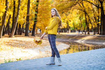 Blonde teenage girl posing in autumn park