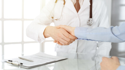 Unknown male doctor and woman-patient discussing current health examination while sitting in clinic and using clipboard. Good medical service in hospital. Medicine concept