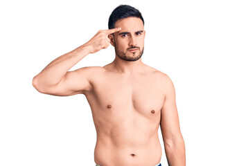 Fototapeta premium Young handsome man wearing swimwear pointing unhappy to pimple on forehead, ugly infection of blackhead. acne and skin problem