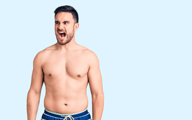 Fototapeta premium Young handsome man wearing swimwear angry and mad screaming frustrated and furious, shouting with anger. rage and aggressive concept.