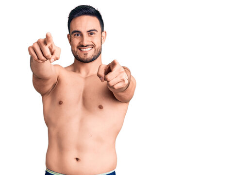 Young handsome man wearing swimwear pointing to you and the camera with fingers, smiling positive and cheerful