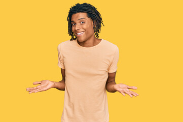 Young african american man wearing casual clothes clueless and confused expression with arms and...