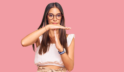 Fototapeta premium Young hispanic woman wearing casual clothes and glasses doing time out gesture with hands, frustrated and serious face
