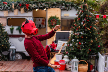 A young man in a bull ox costume is a symbol of the new year against the background of a red car, a...
