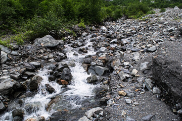 Midagrabindon  waterfalls in the gorge. Mountains in the North Caucasus in summer. Mountain tops in the clouds.