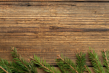 Fir, spruce branches on brown wooden background with copy space