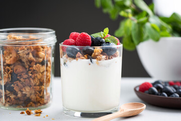 Yogurt granola parfait with berries. Greek yogurt with oat honey granola, raspberries and blueberries in a jar