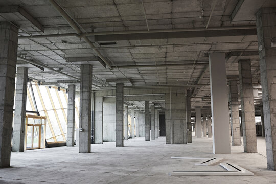 Wide angle background image of empty building under construction with concrete columns, copy space