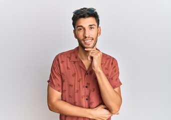 Young handsome man wearing casual summer clothes looking confident at the camera smiling with crossed arms and hand raised on chin. thinking positive.