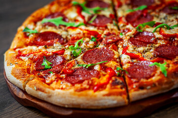 Pepperoni Pizza with Mozzarella cheese, salami, Tomatoes, pepper, Spices and Fresh arugula. Italian pizza on wooden table background