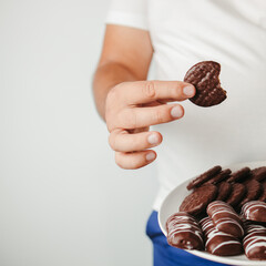 Overweight man snacking with chocolate cookies