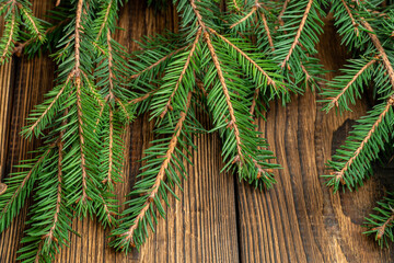 Fir, spruce branches on brown wooden background with copy space