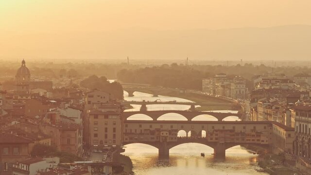 Golden sunset and drone or quadcopter aerial photography of Florence cityscape. Italian old architecture and medieval churches, cathedrals, houses and domes in front of mountain peaks or tops.