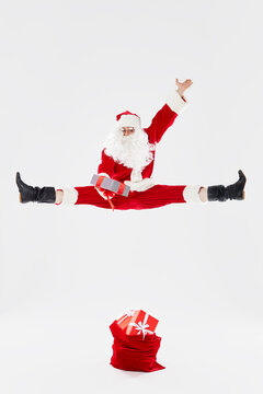 oyful Santa Claus jumps high and dances with happiness with gifts on a white background. Concept for Christmas and New Year holidays and sales.