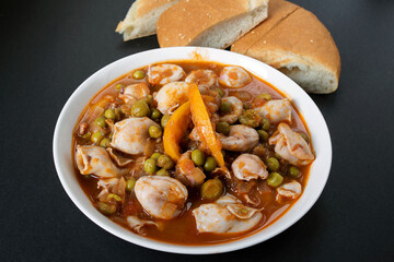 mini squid in tomato sauce with green peas and olives. Moroccan cuisine