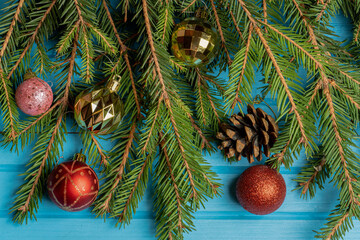 Fir, spruce branches and Christmas tree toys on blue wooden background with copy space
